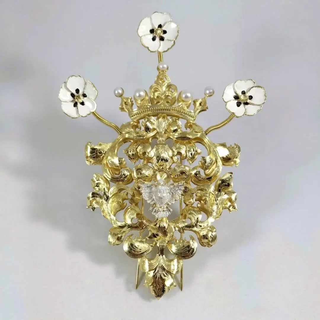 Broche "Rosa acorazonada coronada" en plata de ley chapada en oro con esmaltes y un pequeño relicario con un trozo de manto de la Virgen del Rocío de Almonte. Basado en modelos de joyería antigua (Joyería El Oribe, 2023). Foto extraída de las redes sociales de la Hermandad de la Tercera Caída.