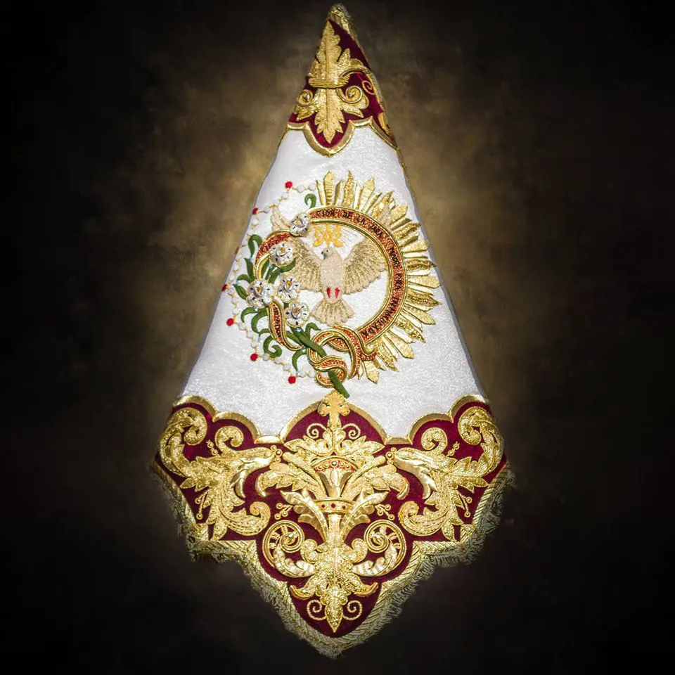Guión de la bendición de María Santísima del Rocío en tisú de plata y terciopelo burdeos combinando bordados en oro y sedas (Ildefonso Jiménez, 2018). En el centro reproduce el logotipo de la bendición de la Virgen diseñado por Alesco. Foto extraída de las redes sociales de la Hermandad de la Tercera Caída.